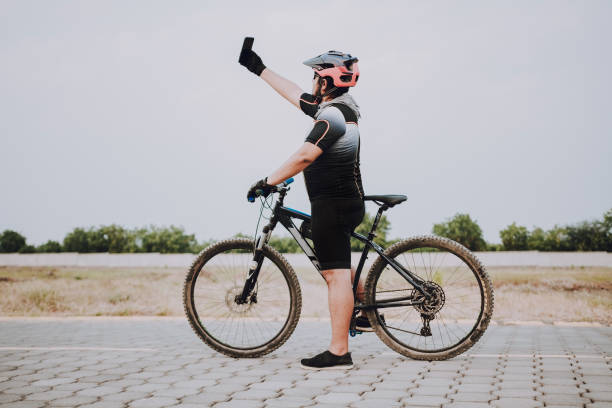Cyclist taking a selfie on his bike. Chubby cyclist in a sports suit taking a selfie on the road Cyclist taking a selfie on his bike. Chubby cyclist in a sports suit taking a selfie on the road ciclismo stock pictures, royalty-free photos & images