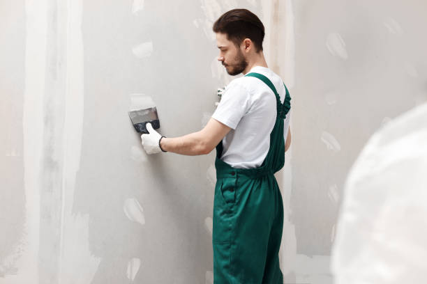 istock Worker in uniform plastering wall with putty knife indoors 1485824485