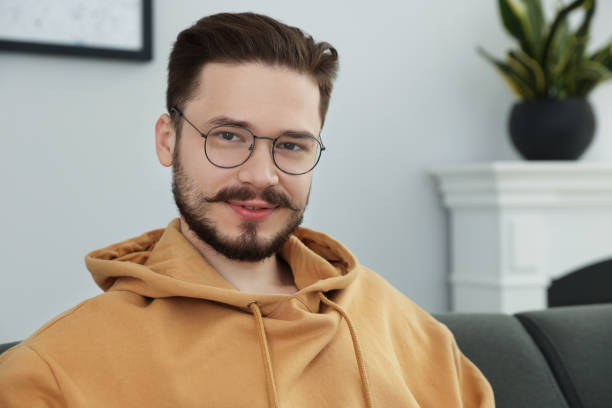 istock Smiling man sitting on grey sofa in room. Space for text 1485824750