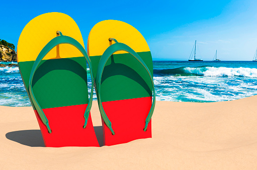 Flip flops with Lithuanian flag on the beach. Lithuania resorts, vacation, tours, travel packages concept. 3D rendering