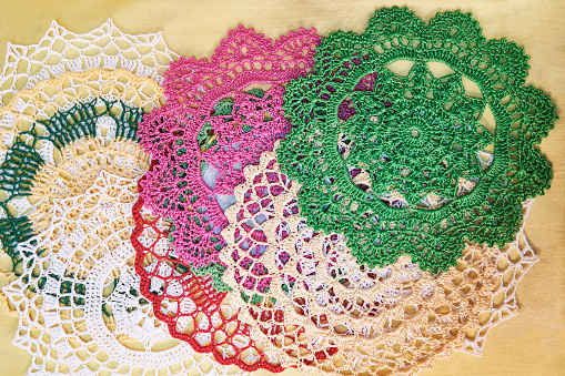 Set of vintage lace colorful round napkins on yellow background. Home craft. Handmade decor. Top view. Flatlay.