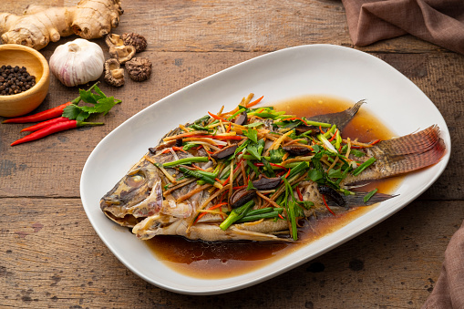 Steamed Tilapia Fish with Soy Sauce in white plate.(Pla neung see ew)