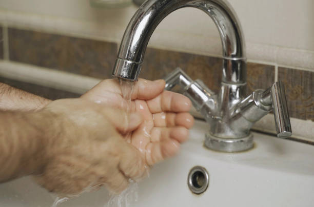 a man washes his hands with water in the bathroom. - water human hand stream clean imagens e fotografias de stock