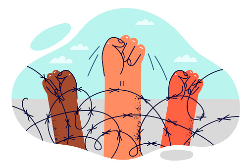 Hands of protesters are clenched into fist near barbed wire at border intended to restrict movement of illegal migrants. Fist is symbol of protest action of prisoners against deprivation of liberty