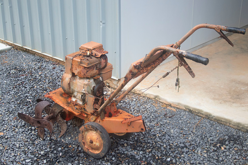 Old Vintage Manual Rotary Hoe Plow outside a garage