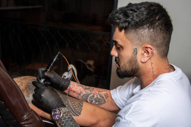 istock Professional tattooer doing tattoo on hand using tattoo machine in studio 1485844839