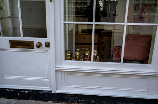 A lovely mews house in the Belgravia section of London England with several decorative copper canisters in the window.