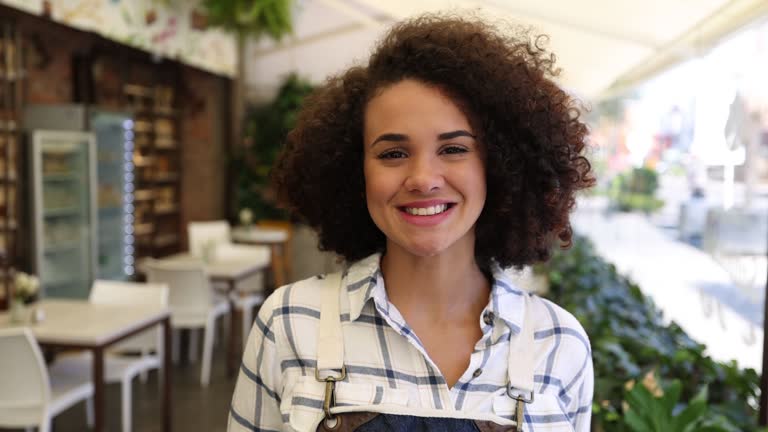 Beautiful diverse woman working at a bakery smiling at camera very cheerfully