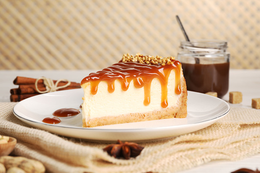 Tasty cheesecake with caramel and nuts served on table