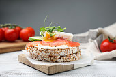 Crunchy buckwheat cakes with salmon, poached egg and cucumber slices on white wooden table