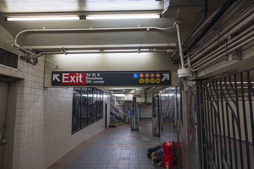 New York, USA. 04.26.2023. Interior view of subway station where homeless man sleeps on floor.