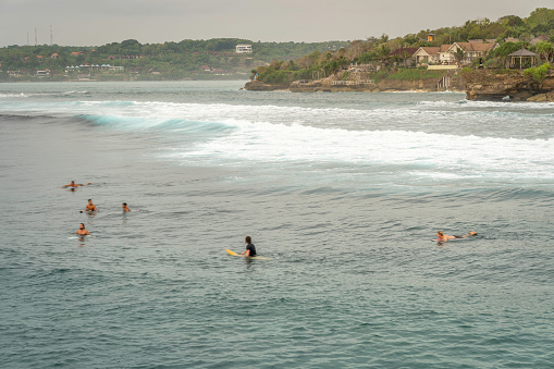 View on Mahana surf spot from Secret point beach with surfers in Nusa Ceningan in Bali