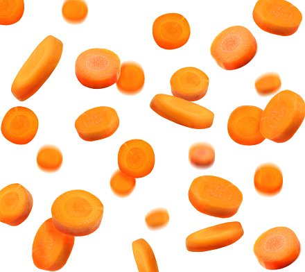 Slices of fresh carrots falling on white background