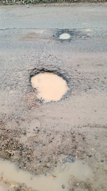 Photo of broken asphalt road. the asphalt road with potholes and waterlogged after the rain