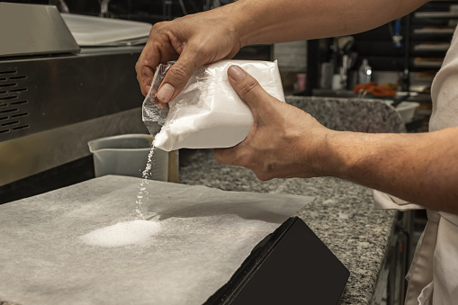 A chef weighing a certain amount of salt to prepare a recipe