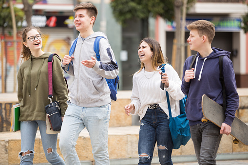 Cheerful teenage boys and girls walking together after lessons