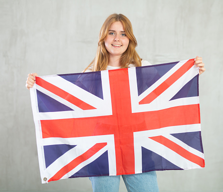 Attractive smiling female football fan holding Great Britain flag