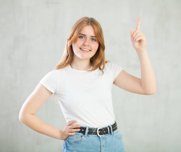 istock Girl point finger at arm with copy space for promotion over studio wall 1485870496