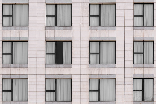 White marble granite facade and multiple windows closed with black metal frames