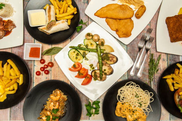 istock Mediterranean dishes and burritos, chicken schnitzel, shrimp rice, cherry tomatoes, curry noodles, French fries, forks, wild asparagus, grilled vegetables 1485877006