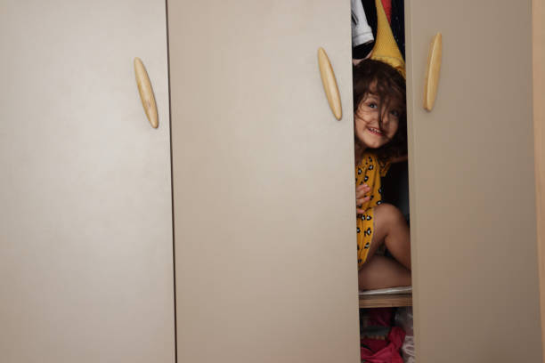Young, pregnant woman standing in front of the closet and organizing her clothes.