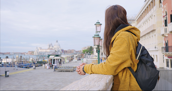 Young female traveler looking the view to a canal in Venice, Italy. Vacation in Europe.
