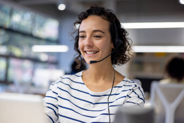 representante de servicio al cliente usando un auricular mientras trabaja en un centro de llamadas - bluetooth headset women hands free device fotografías e imágenes de stock