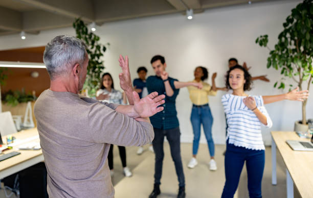 Man leading a group of workers stretching on an active break at the office