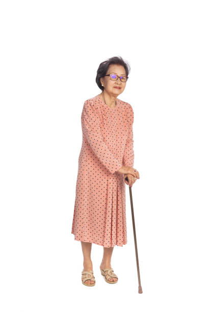 Old woman suffering from low back pain on a white background , standing with walking stick