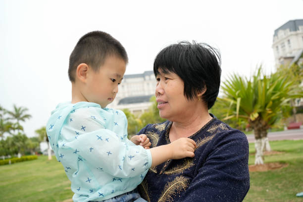 Grandmother and her two grandchildren are sharing a moment together outdoors