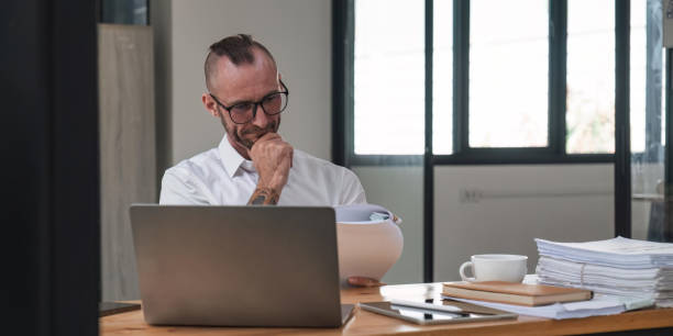 istock Serious financier accountant on paper work inside office, mature man using laptop for calculating reports and summarizing accounts 1485925208