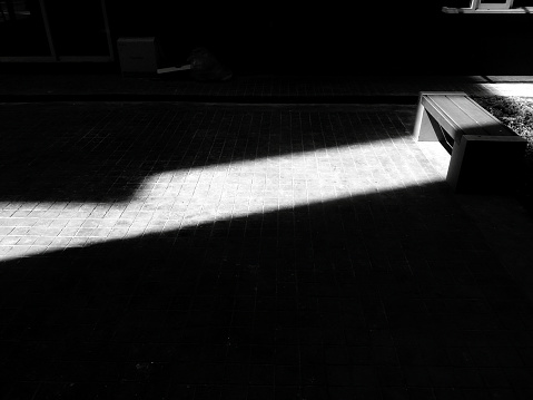Wooden bench with shade of sunlight and shadow in black and white tone. Object and Art of monochrome photo