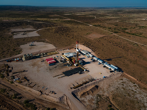 Drone view captures the Permian Basin at sunset, revealing the sprawling landscape of fracking drilling and oil rigs that stretch out towards the horizon