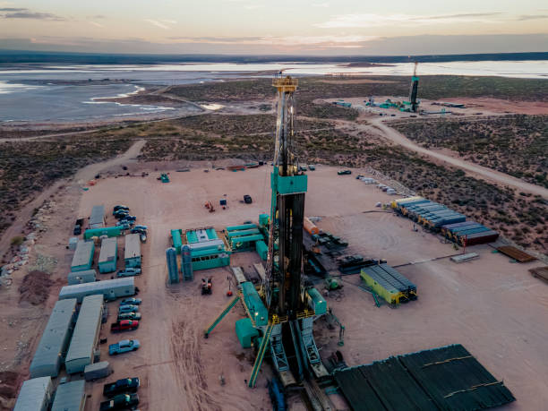 drone captura una impresionante puesta de sol sobre la cuenca del pérmico, mostrando una plataforma petrolera perforando y fracturando el fracking en busca de petróleo, en medio de la inmensidad del paisaje - oil industry industry new mexico oil drill fotografías e imágenes de stock