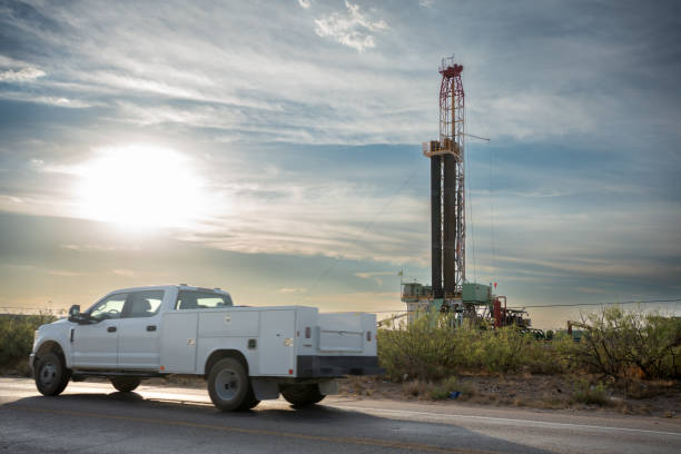 truck passes by an oil drilling platform with a fracking rig in operation, extracting fuel to meet the world's demands - oil industry industry new mexico oil drill imagens e fotografias de stock