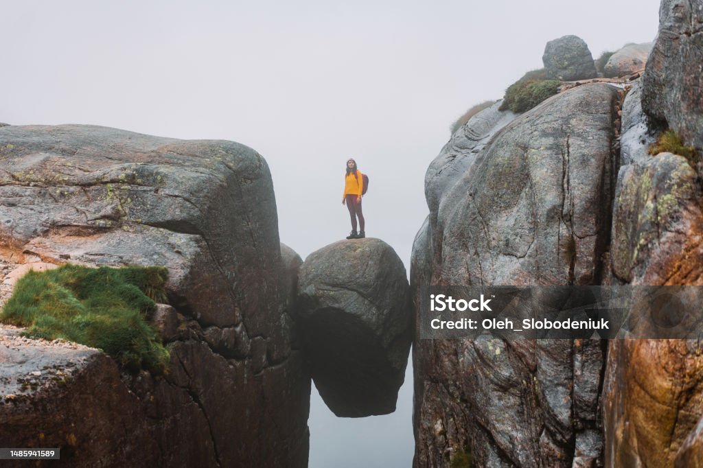 Woman standing on Kjeragbolten Young Caucasian woman standing on Kjeragbolten  in Norway Cliff Stock Photo
