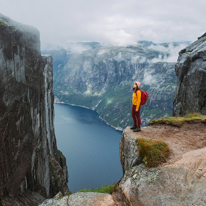 Woman in yellow sweater with backpack on the background of Lysefjorden
