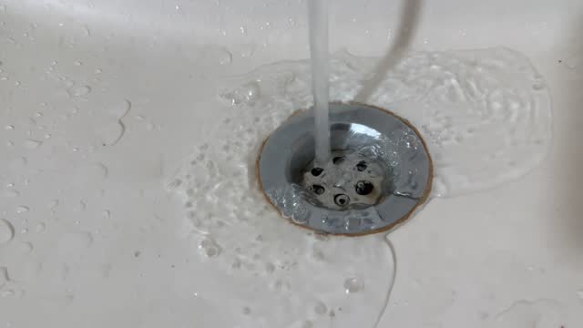 Close-Up of water swirling down the ceramic basin drain hole