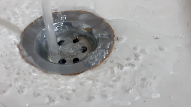 Close Up of Water flows down in sink drain hole