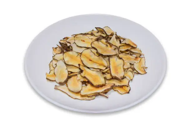 Homemade organic Jerusalem artichoke chips snack on a white plate isolated on a white background with clipping path.