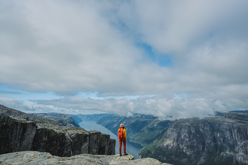 Woman in yellow sweater with backpack on the background of Lysefjorden