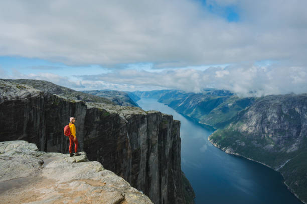 hiking norway Woman in yellow sweater with backpack on the background of Lysefjorden lysefjorden stock pictures, royalty-free photos & images