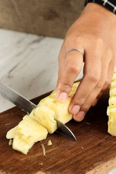 istock Female Hand Slicing Pineapple into Slices 1485952889