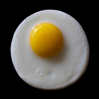Close-up of an appetizing fried egg on a black background, top view