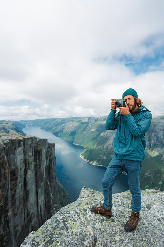 Man in blue raincoat  photographing  Lysefjorden from Kjerag mountain