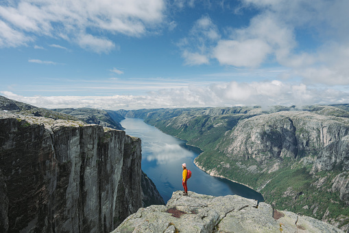 Woman in yellow sweater with backpack on the background of Lysefjorden