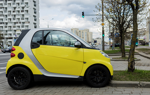 Minsk, Belarus, April 2023  - side view of a yellow small Mercedes smart parked in the city