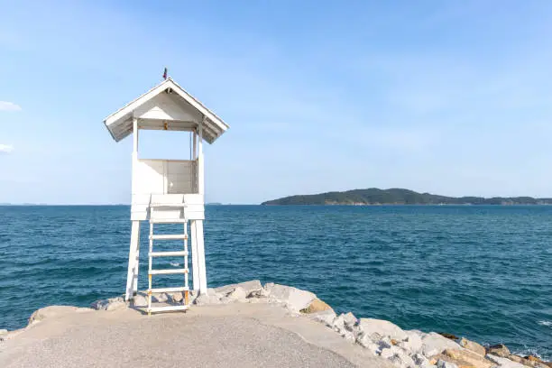 Photo of Little white wooden observation tower with background of blue ocean