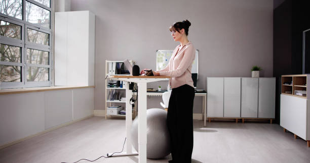 istock Woman Using Adjustable Height Standing Desk In Office 1485961831