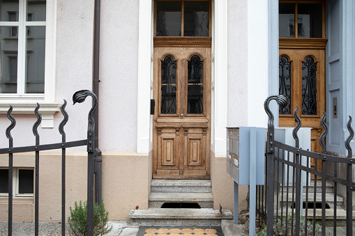 Modern house facade with stone finished wall, glass door and bushes in europe.